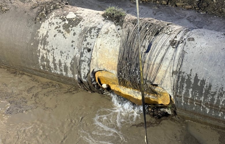 A massive water main is shown, damaged and exposed.