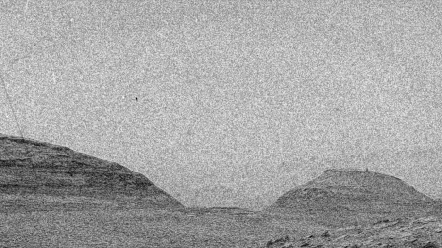a grainy black and white image of a distant hill
